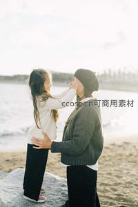 海边岩石上母女嬉戏，阳光洒满笑脸