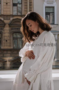 孕妇窗边轻抚腹部凝望远方