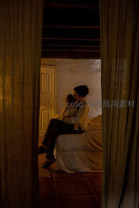 门缝窥见母亲怀抱婴儿，暖光中静谧安眠