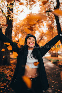 秋日林间，女子欢笑抛洒落叶