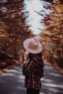 秋日林间小径，女子戴帽回眸