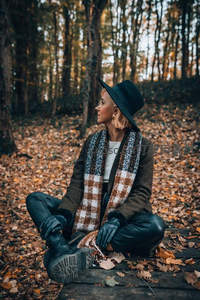 森林落叶中沉思的时尚女子