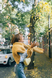 街头少女抛洒黄叶，欢笑迎接秋意