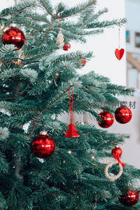 特写圣诞树装饰，红球心形吊饰点缀绿意