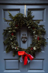 灰色门上悬挂的圣诞花环，点缀红果与丝带