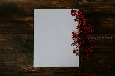 木质背景上的白纸与红浆果装饰