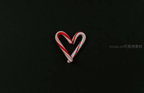 两根拐杖糖组成的爱心形状在黑色背景上