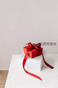 红色丝带礼盒静置于白色桌面之上