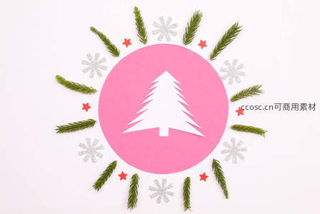 粉色圆形背景中的白色圣诞树与松枝环绕