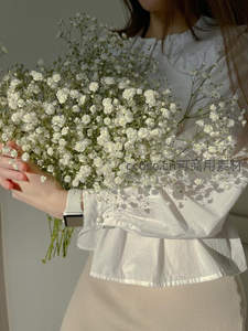白衣女子手捧满天星花束优雅静立