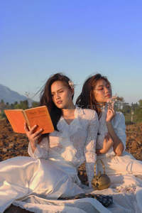 田野野餐两位白衣女子读书赏花