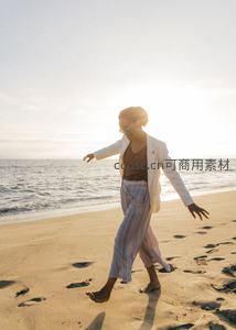 沙滩漫步白衣女子，逆光剪影踏浪花