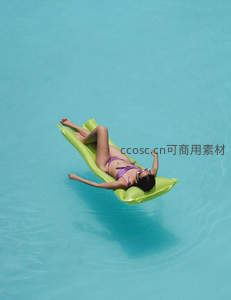 俯拍视角下，女子悠然漂浮于碧蓝泳池之上