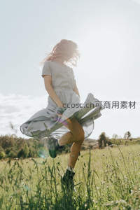 少女在阳光下的草地上跳跃