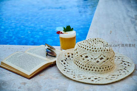 泳池边的悠闲时光，书本与鸡尾酒相伴