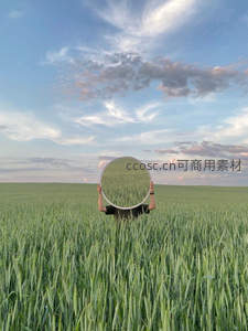 麦田中手持圆镜，倒映天空云彩奇景