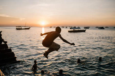 夕阳下少年跃入海中溅起水花