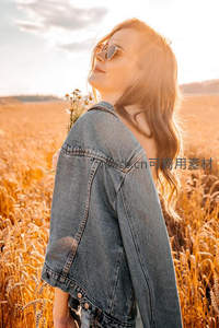 金发女子立于麦田沐浴夕阳余晖