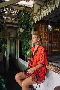 红衣女子手持绿饮，热带风情庭院小憩