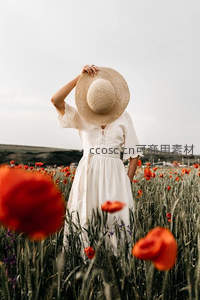 草帽遮面女子伫立花丛间