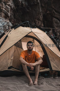 沙滩岩壁下露营的男子