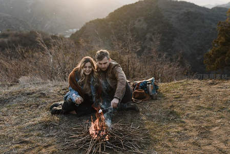 山巅之上，情侣共烤棉花糖，夕阳为爱意镀金。