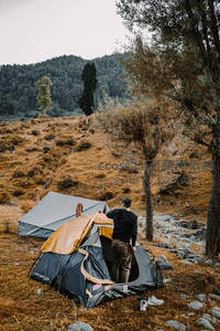 山野溪畔男子搭建帐篷准备野外露营