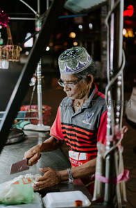 夜市摊主戴帽切菜专注准备街头小吃