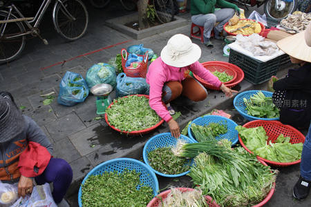 菜市场妇女蹲地整理新鲜蔬菜