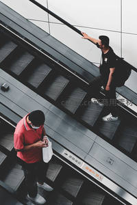 商场扶梯上的日常瞬间，两人各自忙碌