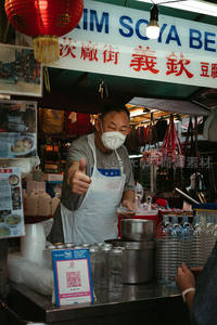 戴口罩摊主微笑竖起大拇指卖豆腐
