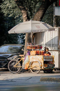 树荫下三轮车小吃摊贩售卖色彩缤纷的零食