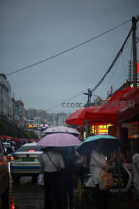 雨天街市行人撑伞，红棚摊位林立