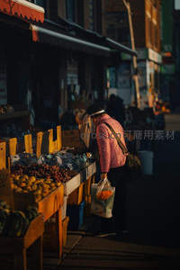 夕阳下顾客挑选新鲜水果的街边摊