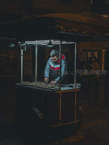 夜市灯火下的烤栗子小贩