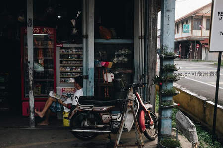 街角小店门前悠闲阅读的少年