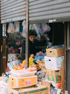 日本花店老板在卷帘门后整理鲜花与水果