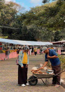 户外集市交易，男子向顾客展示木薯农产品
