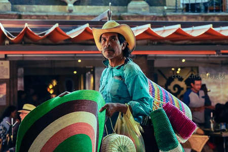 街头小贩肩扛彩色草帽，目光炯炯有神