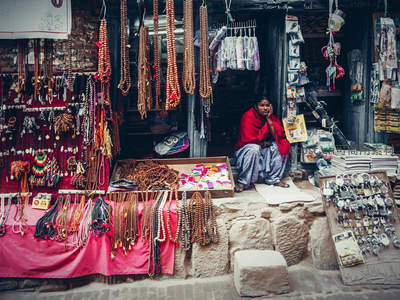 手工艺品摊前，披着红巾的女子静候顾客光临