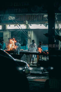 深夜路边烧烤摊，火焰升腾照亮忙碌的夜宵时光