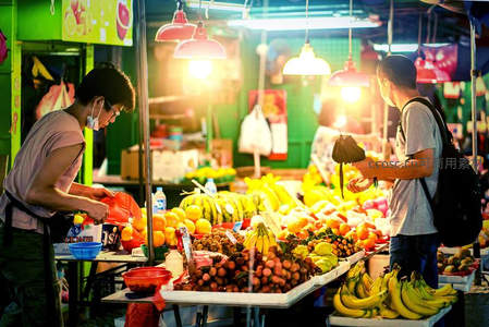 夜市水果摊前顾客挑选热带水果