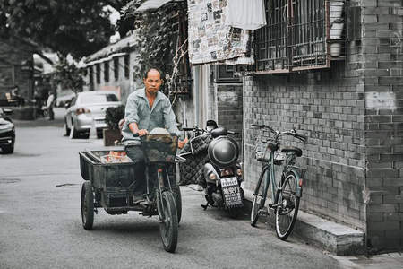 三轮车夫穿行于胡同，运送货物的日常