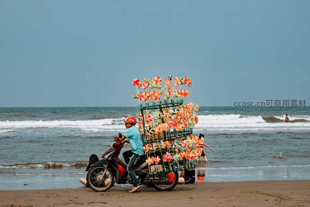 海边摩托载花商，浪花与风车共舞