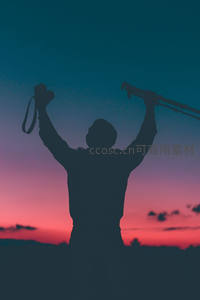 剪影摄影师高举相机迎接日落