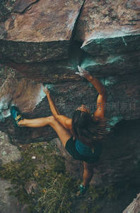 女子攀岩者在陡峭岩壁上奋力向上攀登