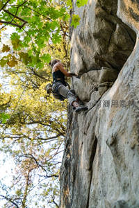 林间岩壁上的女性攀岩者专注向上