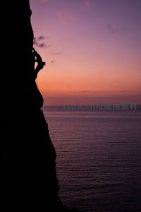 日落时分悬崖剪影中的攀登者