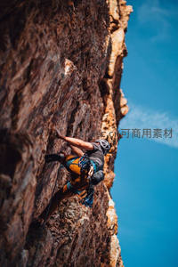 极限攀登者挑战陡峭岩壁，蓝天为幕