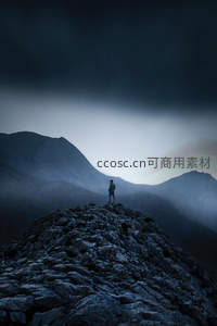 剪影人物屹立于风暴来临前的山巅